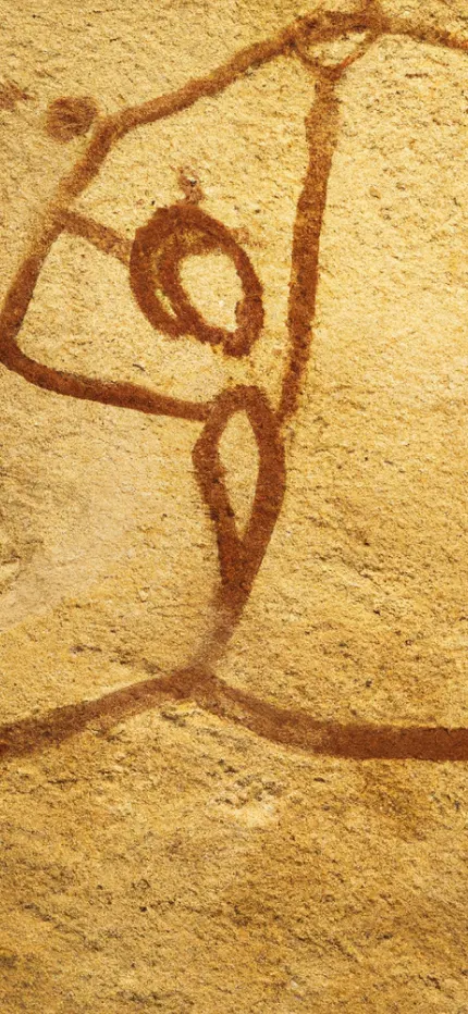 Rust-red painted figure with a round eye, drawn on rough sandstone like a cave painting